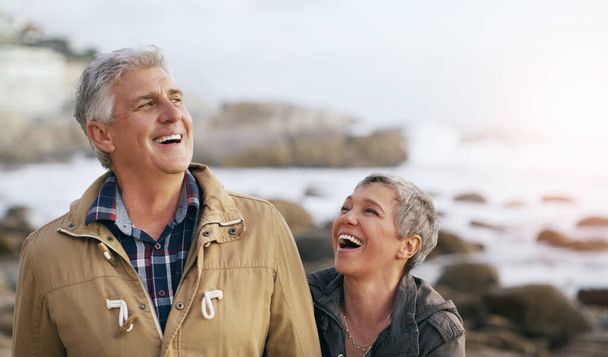 Мы всегда смеялись вместе. Снимок красивой пожилой пары, гуляющей по пляжу. - Фото, изображение