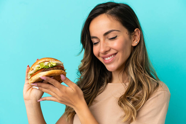 Young woman holding a burger over isolated background - Фото, зображення