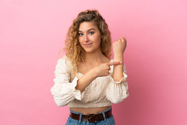 Young blonde woman isolated on pink background making the gesture of being late - Photo, Image