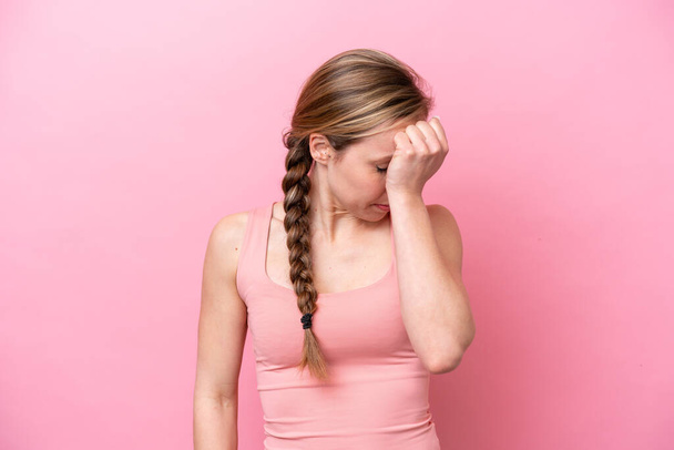 Young caucasian woman isolated on pink background with headache - 写真・画像