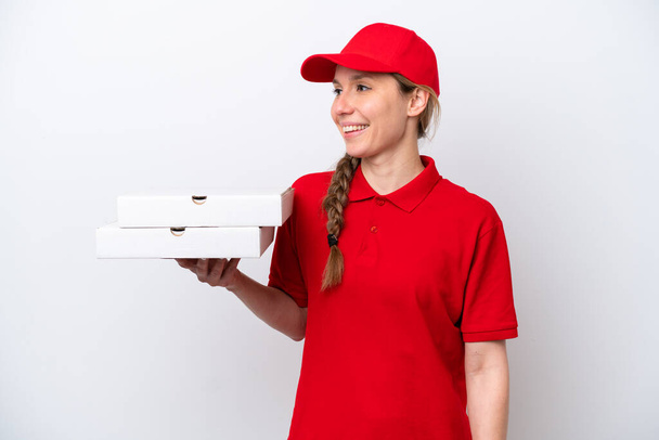 Pizza delivery γυναίκα με στολή εργασίας μαζεύοντας κουτιά πίτσα απομονώνονται σε λευκό φόντο αναζητούν πλευρά - Φωτογραφία, εικόνα