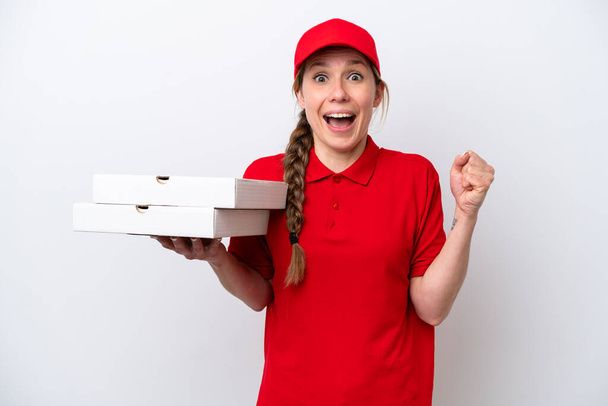 Pizzabote in Arbeitsuniform nimmt Pizzakartons isoliert auf weißem Hintergrund entgegen und feiert einen Sieg in der Siegerposition - Foto, Bild