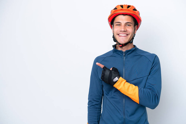 Young cyclist caucasian man isolated on white background pointing to the side to present a product - Photo, Image