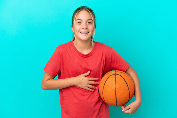 Little caucasian girl playing basketball isolated on blue background smiling a lot - Foto, imagen