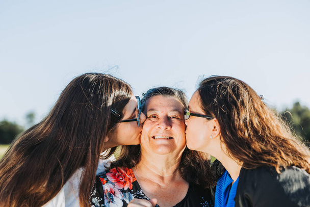 Женская семья улыбается и целуется в поле в солнечный день. День матери. - Фото, изображение