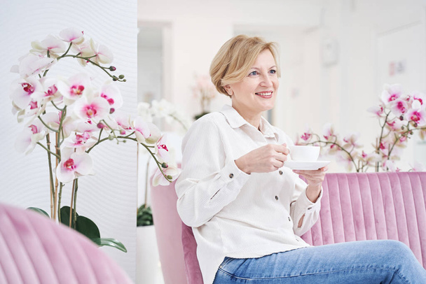 Cute mature blonde woman enjoying aroma coffee - Foto, Imagem