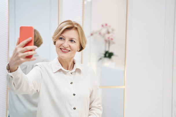 Beautiful senior female posing on camera of her gadget - Photo, Image