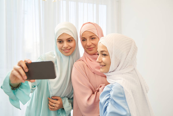 Renkli tesettürlü neşeli bayanlar selfie çekiyorlar. - Fotoğraf, Görsel