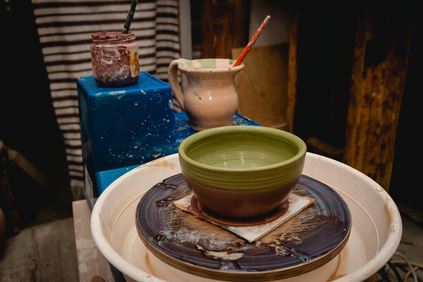 Pottenbakker werkt aan pottenbakkerswiel met klei. Proces van het maken van keramische servies in aardewerk workshop. Ambachten en kunst concept. - Foto, afbeelding