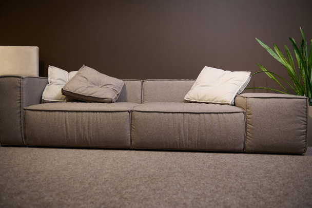 Vista frontal de un gran sofá cómodo hecho de telas de alta calidad y cojines suaves, en exhibición en la sala de exposición de una tienda de muebles. Inicio diseño de interiores, decoración de la sala de estar - Foto, imagen