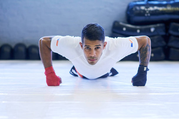 Building my strength for the next fight. Portrait of a young man doing pushups in the gym. - Photo, Image