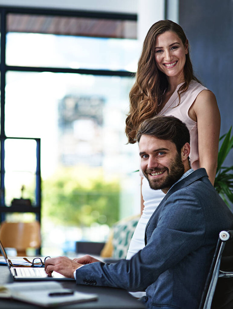 El trabajo duro es nuestro secreto para el éxito. Retrato de empresarios trabajando juntos en un portátil en una oficina moderna. - Foto, imagen