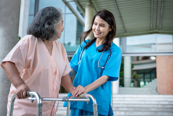 Mujer asiática médico cogido de la mano, animó y apoyó a la paciente, que tiene un bastón, hacer fisioterapia para caminar, al seguro de salud y el concepto de osteoartritis. - Foto, Imagen