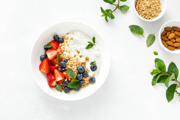Breakfast bowl with granola, plain yogurt, strawberry and blueberry, top view - Fotó, kép