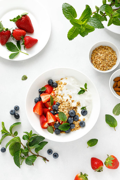 Breakfast bowl with granola, plain yogurt, strawberry and blueberry, top view - Zdjęcie, obraz