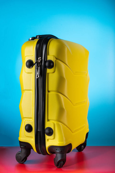 Жовта валіза на колесах на синьому фоні. Вид збоку валізи. Кінець сумки на колесах
. - Фото, зображення