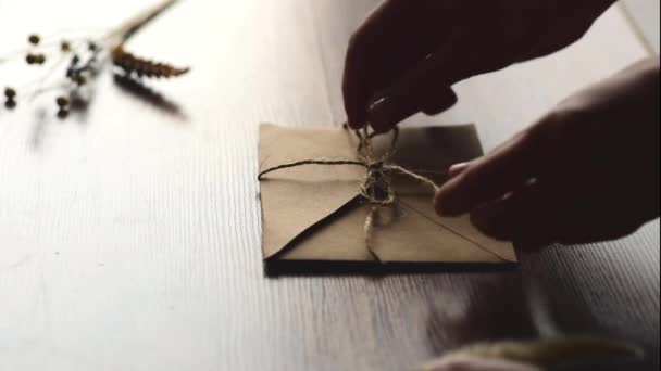 Womens hands open kraft envelope on wooden background - Footage, Video