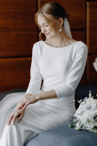 Beautiful gentle girl in a wedding dress on the bed waiting by the window. High quality photo - Valokuva, kuva