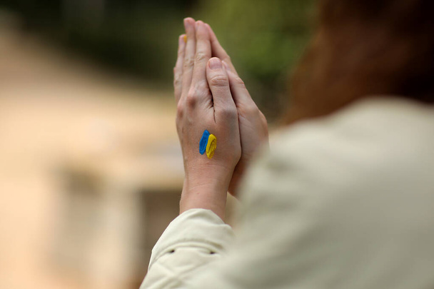 Stop War. Peace in Ukraine. woman hands with picture of flag of ukraine, hands folded in prayer. Antiwar support concept. High quality photo - Photo, Image