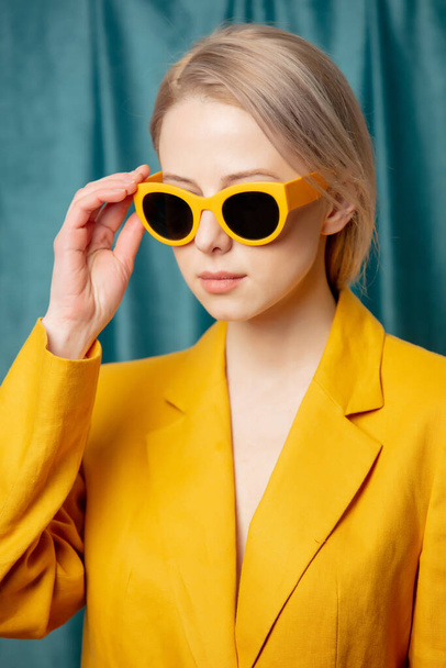 Stylish ukrainian woman in yellow sunglasses and jacket on green curtains background - Фото, изображение