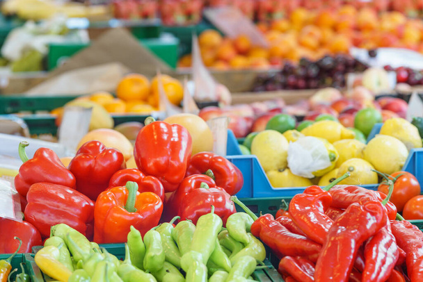 Groep van groene en rode paprika en citrusvruchten op de achtergrond op marktkraam - Foto, afbeelding