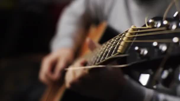 Un jeune homme écoute une guitare acoustique arrachant les cordes et les notes musicales - Séquence, vidéo