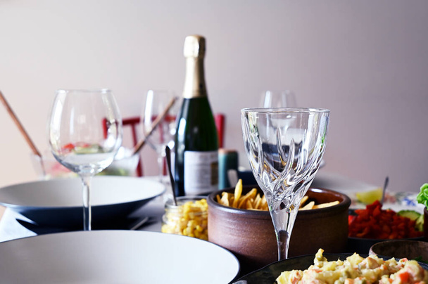 neotevřená láhev vína, prázdné sklenice od vína a postranní talíře na stole - Fotografie, Obrázek