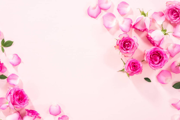 平置きだ。ピンクのバラとバラの花びらがピンクの背景に. - 写真・画像