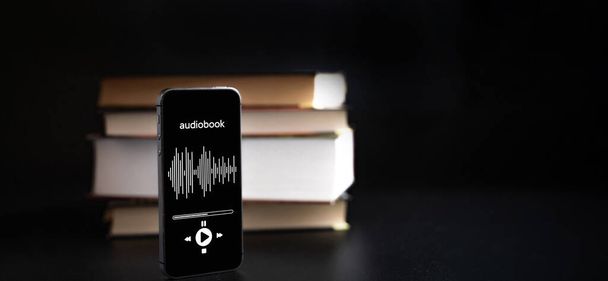 Audio book education. Phone screen with audio book app on paper books black background. Online learning, home school concept. - Photo, Image