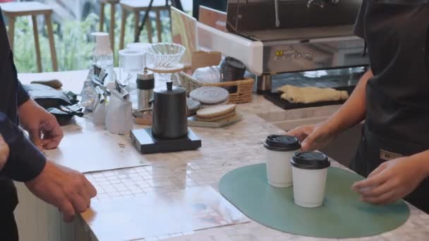 Jonge barista serveert bestellen koffiebeker aan de klant man en vrouw tijdens het afhalen in het cafe, personeel of serveerster service en het geven van koffiebeker aan de klant, kleine bedrijven, KMO of startup business. - Video