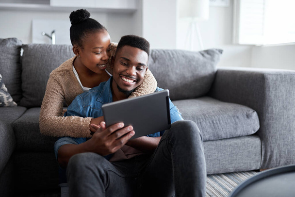 Sharing in a very special connection. Shot of a young couple using a digital tablet together while relaxing at home. - Foto, immagini
