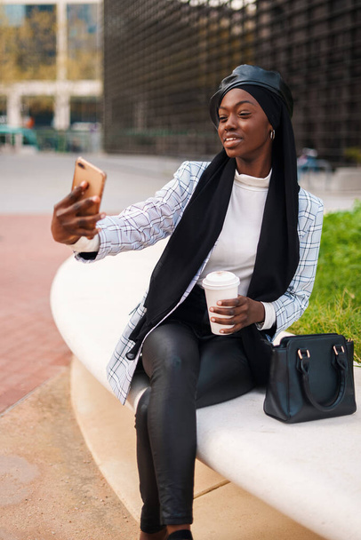 Positivo elegante musulmán negro mujer tomando selfie en el teléfono inteligente - Foto, Imagen