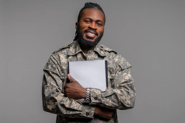 Joyful military man with documents looking ahead - Фото, изображение