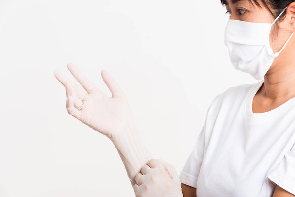 Woman wearing and putting hand to white rubber latex surgical medical glove for doctor and fave mask protect, studio shot isolated on white background, Hospital medical infection control concept - 写真・画像