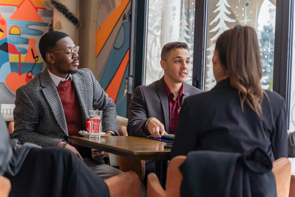 Group of multiracial business people are having a serious discussion about their business new plans and ideas while sitting in the cafe - Фото, зображення