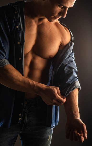 Atractivo y guapo chico está posando y la fijación de su camisa de manga, de cerca - Foto, imagen