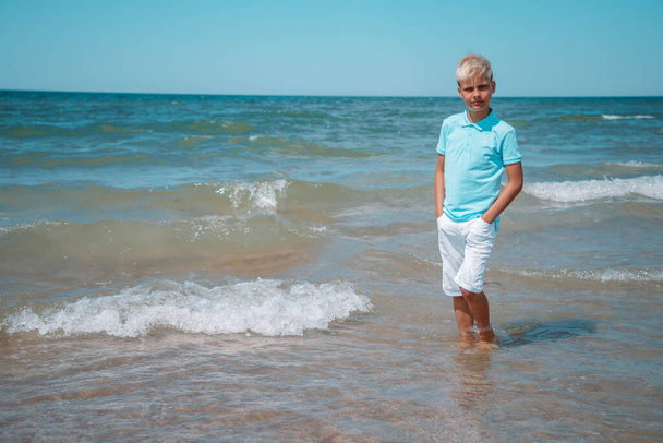 tiener jongen op de zomer roeping staat in de zee in het water - Foto, afbeelding