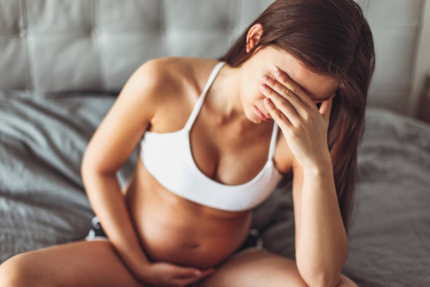 Депресія вагітності. Сумна вагітна жінка почувається втомленою або має головний біль, ранкову хворобу, стрес, розлад сну. Концепція психічного здоров'я
 - Фото, зображення