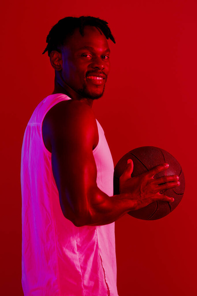 Tedd magad büszkévé. Piros szűrt lövés egy fiatal sportoló pózol egy kosárlabda a stúdióban. - Fotó, kép