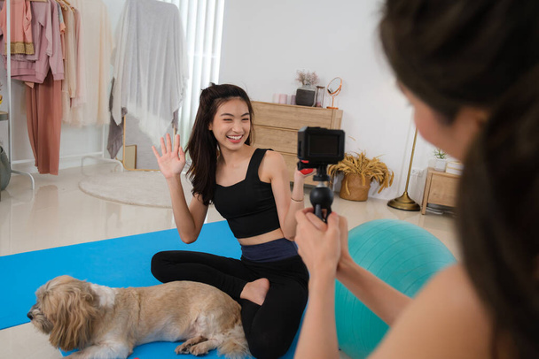 Genç bir çift Asyalı kadın köpeğiyle antrenman yapmak ve oynamak için evde uzun zaman geçirir.. - Fotoğraf, Görsel
