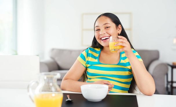 Get the day going with an awesome breakfast. Portrait of a happy young girl enjoying a healthy breakfast at home. - Foto, immagini