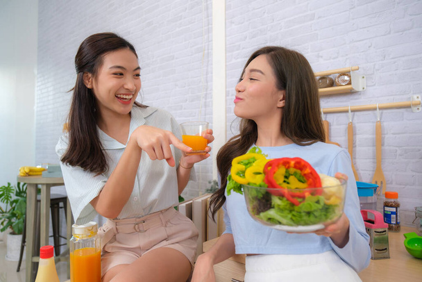 młody Azji para kobiety cieszyć się dla gotowanie sałatka w domu. - Zdjęcie, obraz