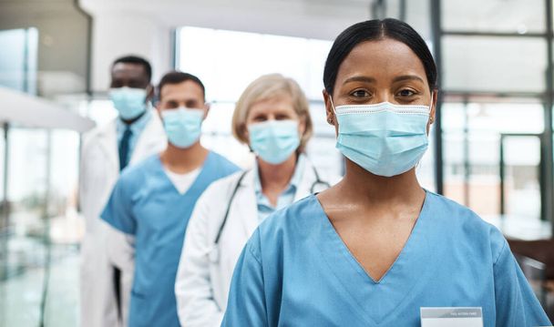 As medical professionals, we have such an important job to do. Portrait of a group of medical practitioners wearing face masks while standing together in a hospital. - 写真・画像