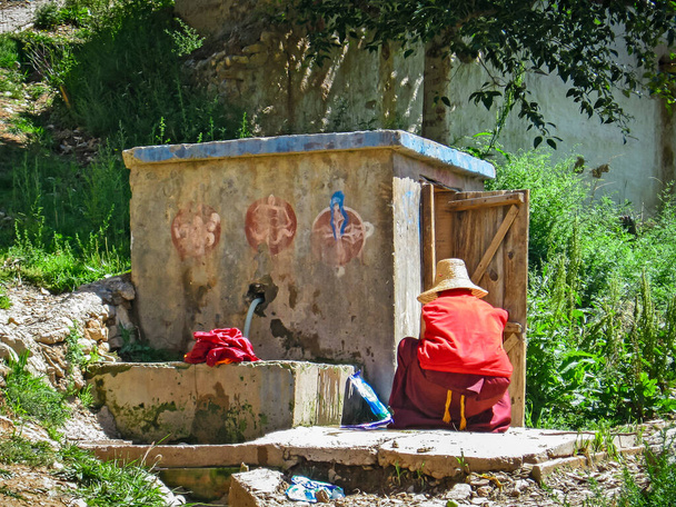 Old Tibetan monk washing clothes - Photo, Image