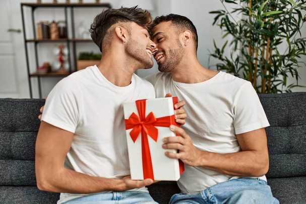 Two hispanic men couple smiling confident surprise with gift at home - Foto, Imagem
