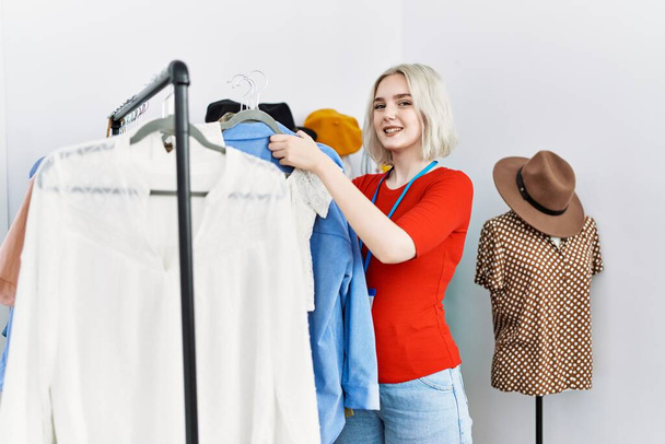 Молода біла жінка посміхається впевнено працює в магазині одягу
 - Фото, зображення