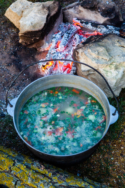 Sopa de pescado preparada sobre fuego abierto. Cocinar sopa de pescado sobre una fogata abierta en una tetera. Cocina en el turismo de senderismo y la pesca - Foto, Imagen