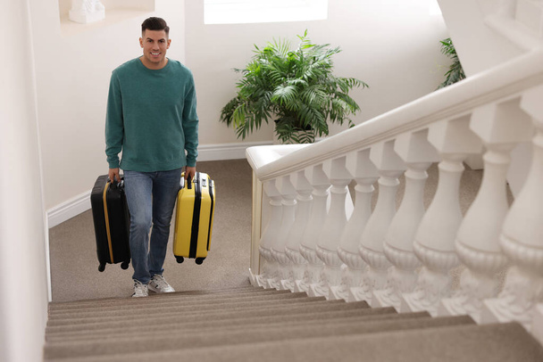 Handsome man with suitcases going up stairs in hotel - Foto, Imagen