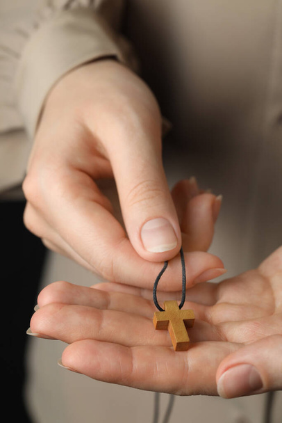 Woman holding wooden Christian cross, closeup view - Fotografie, Obrázek
