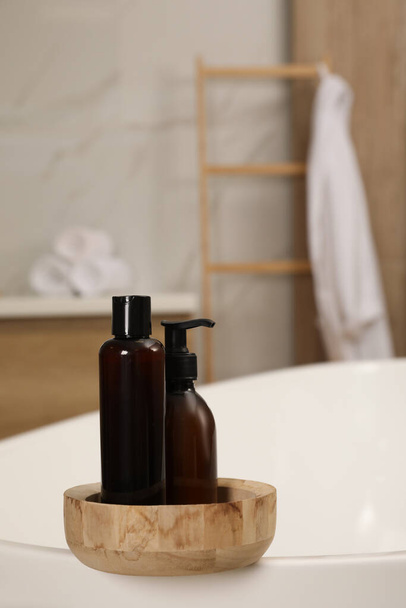 Bowl with bottles of shower gels on tub in bathroom, space for text - Foto, Imagem